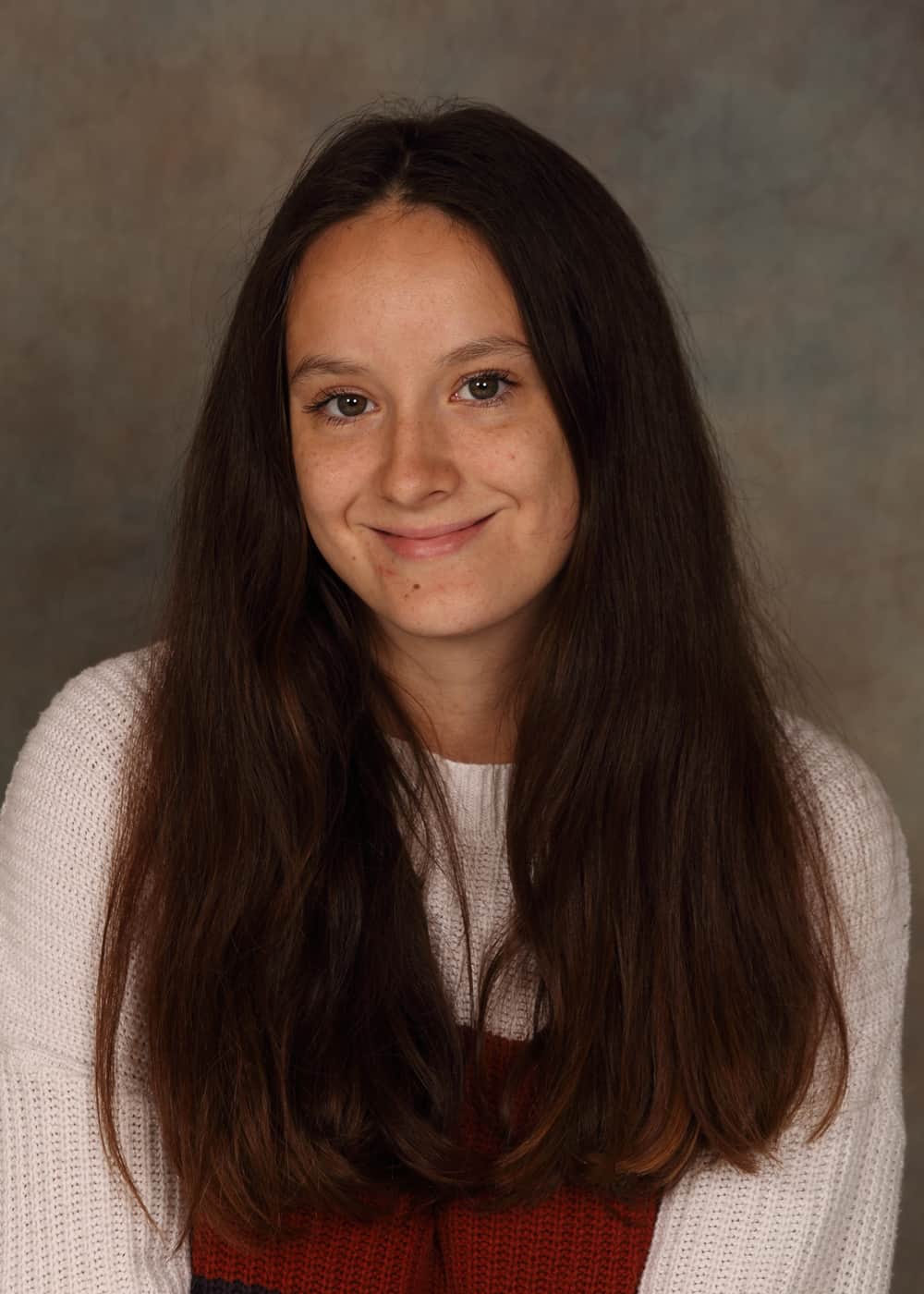 Photo of Co-Teacher Arianna McCorkle. She is a Caucasian woman with long brown hair and green eyes. She is smiling and wears a red and white dress.