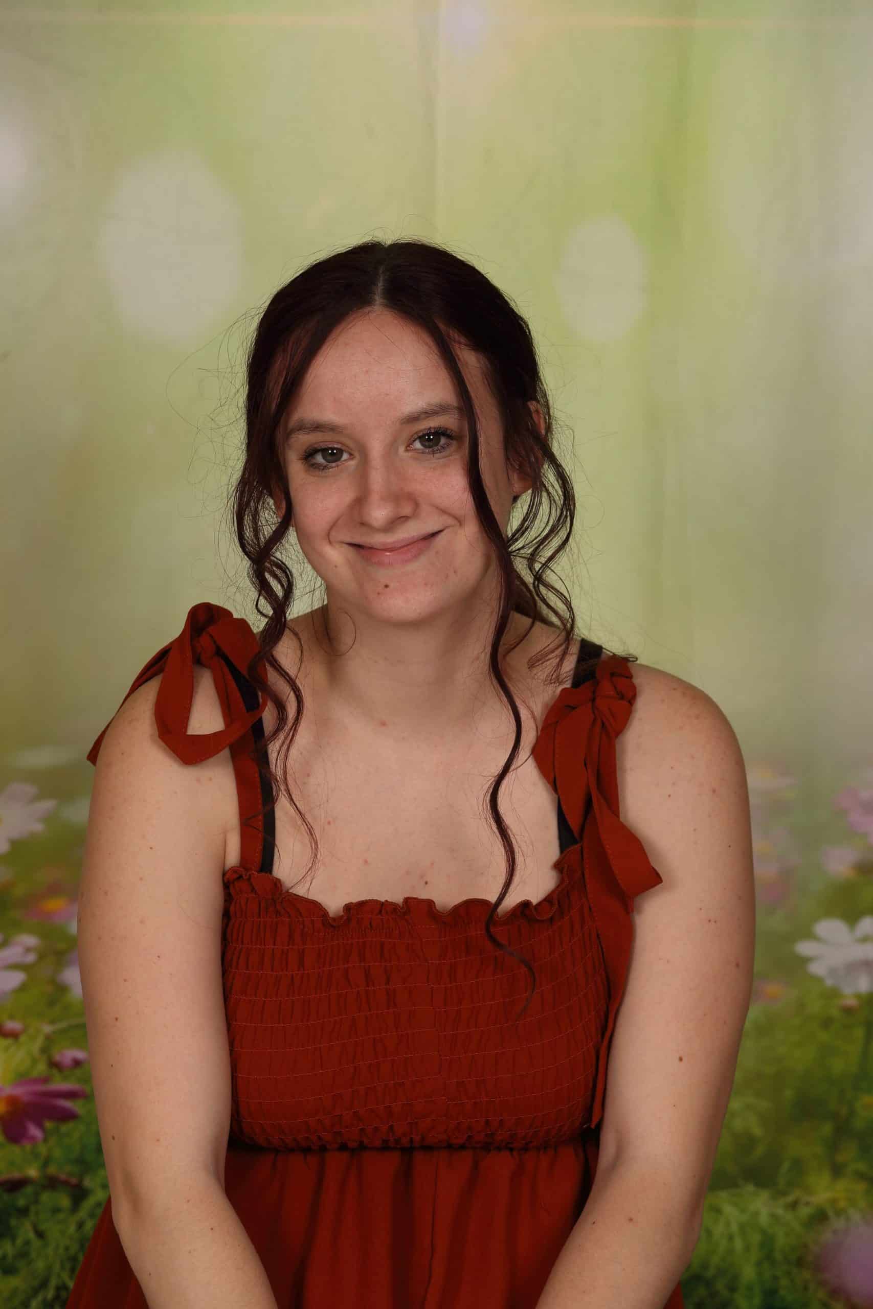 Photo of Co-Teacher Arianna McCorkle. She is a Caucasian woman with long brown hair and green eyes. She is smiling and wears a red dress.